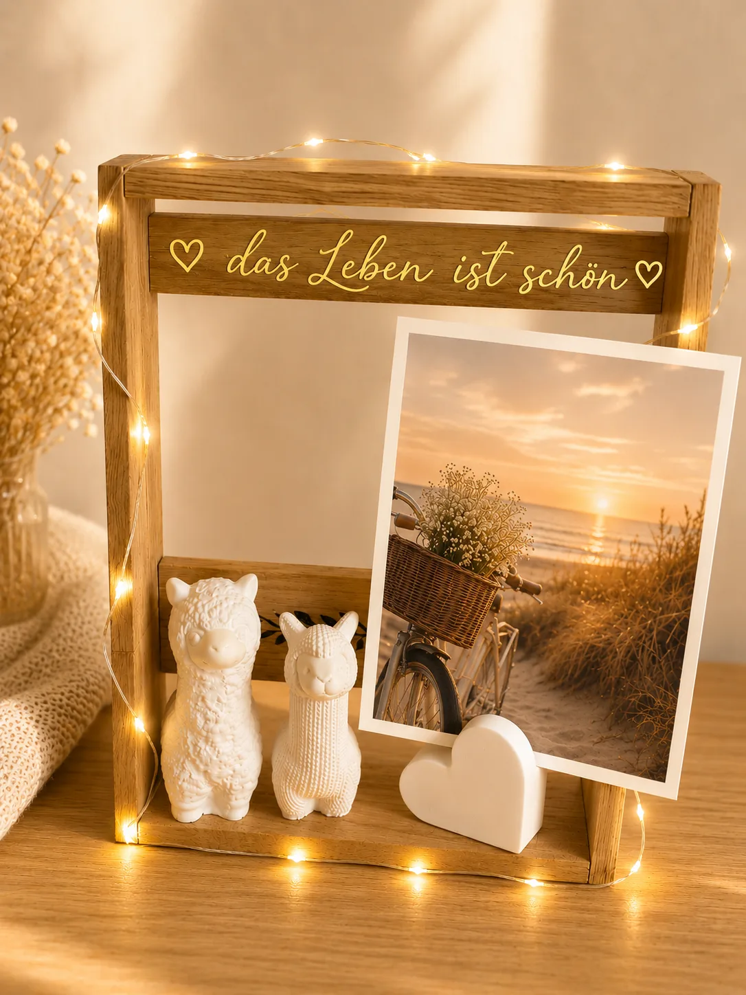 Holzrahmen mit Lichterkette und dem Schriftzug „das Leben ist schön“, mit Alpaka-Figuren, Herz und Foto